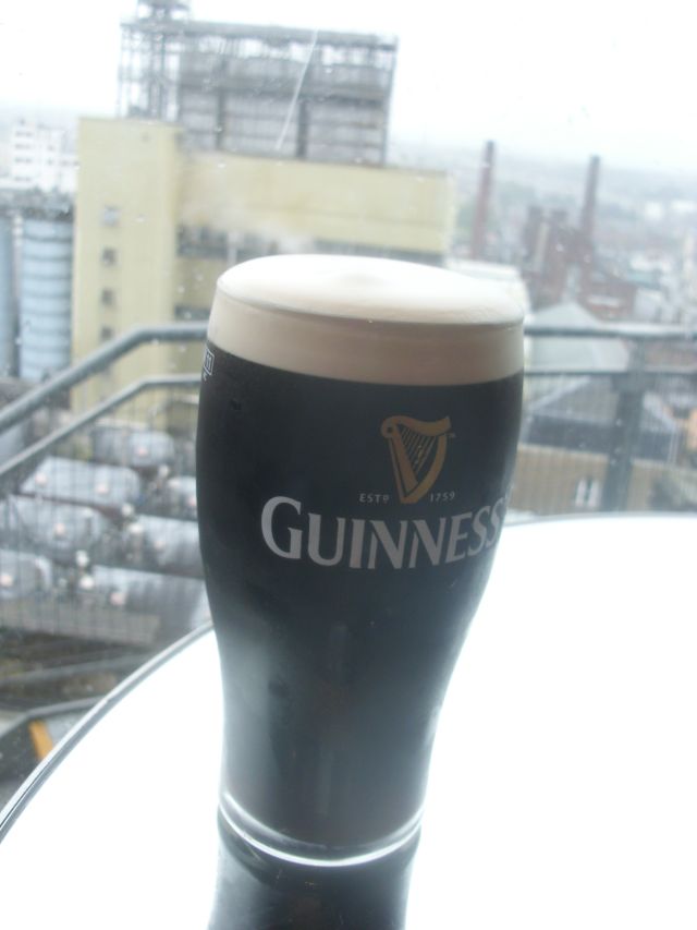 Bierglas Guinness mit Bauerei im Hintergrund